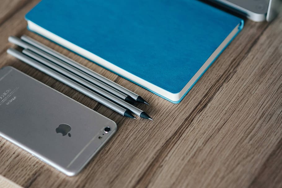 Silver iPhone with a blue notebook and pencils, Apple, mobile HD wallpaper