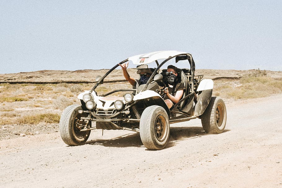man riding UTV on road, two men riding on dune buggy, desert