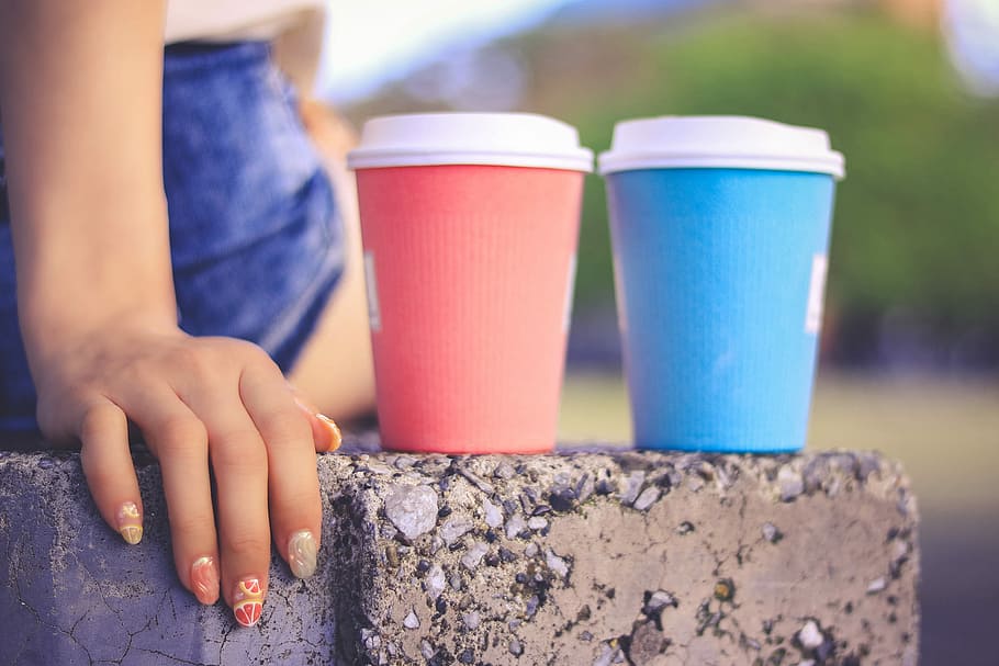 two pink and blue disposable drinking cups beside each other on gray concrete bench HD wallpaper