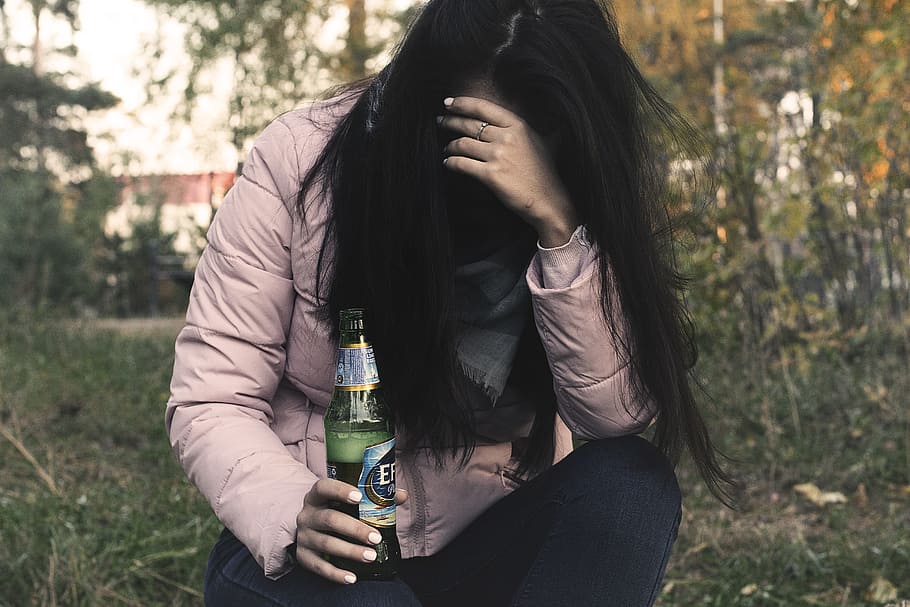 woman holding beer while holding her head, female alcoholism