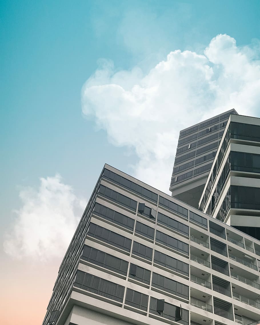 close-up photography of curtain wall building during daytime, low angle-view photography of high rise building under blue sky HD wallpaper
