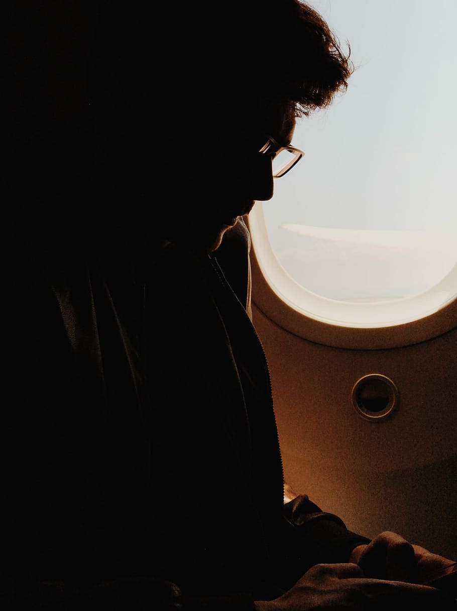 silhouette photography of man sitting in airplane seat, man beside plane window