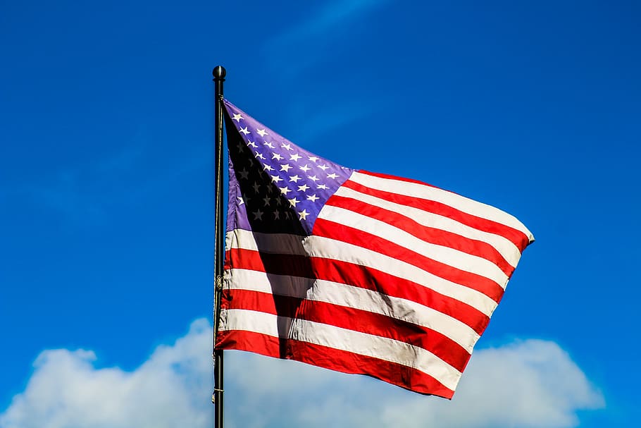 U.S. American flag under clear blue sky, USA flag on pole under blue and white cloudy sky