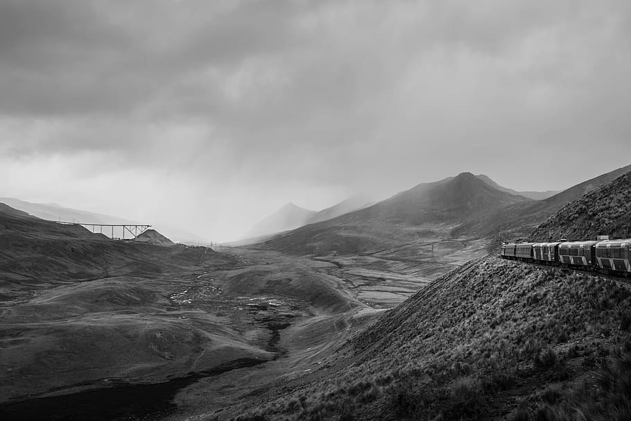grayscale photo of train beside of mountain during cloudy sky, grayscale photo of train traveling a mountain HD wallpaper
