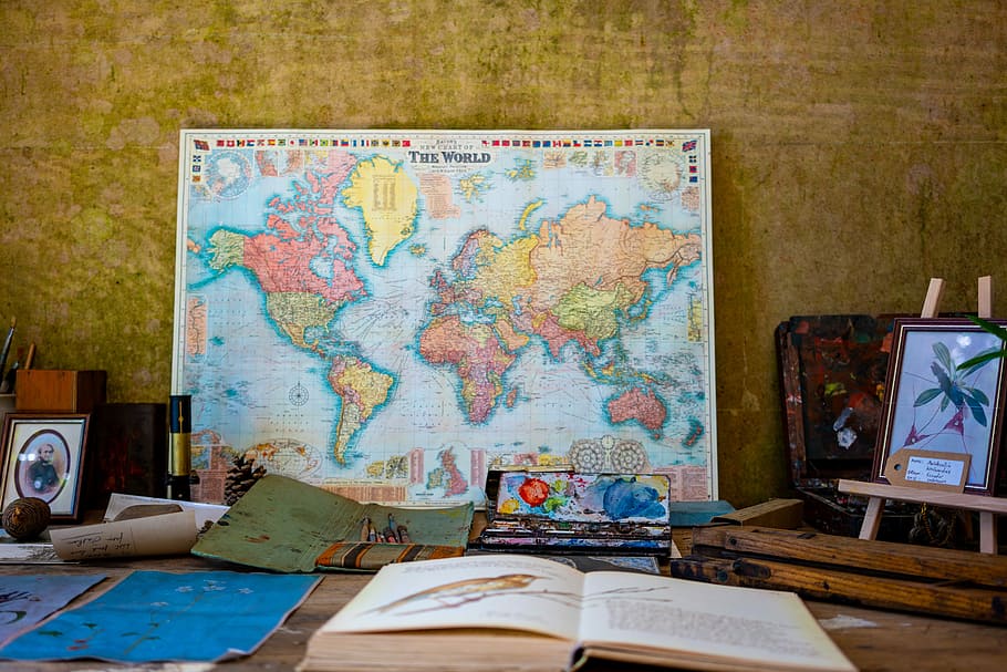 world map poster near book and easel, multicolored map poster beside flower framed painting and opened book HD wallpaper