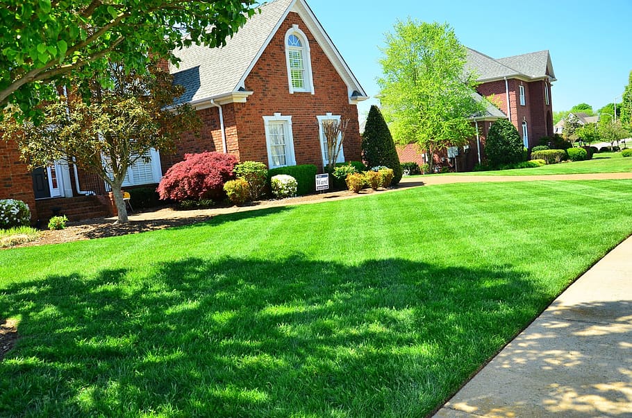 brown brick house near green grass field, lawn care, lawn maintenance