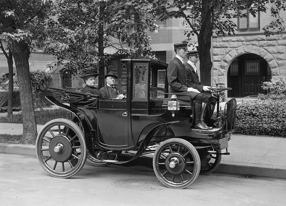 grayscale photograph of three men and one woman riding classic black vehicle HD wallpaper