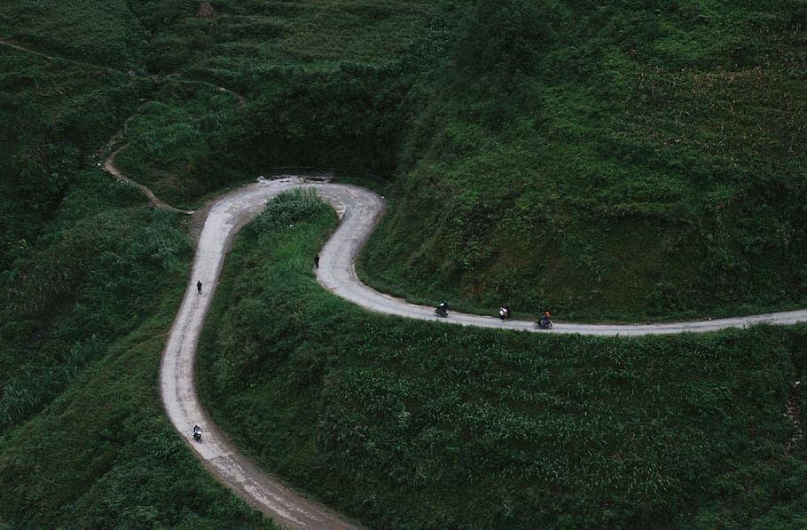 aerial view of curved road beside mountains during daytime, bird's eye photography of mountain and asphalt toad HD wallpaper
