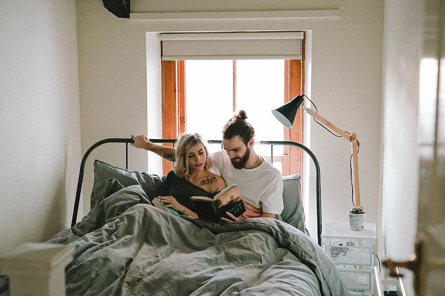 man and woman reading book on bed, man sitting on bed beside woman reading a book inside white painted room, HD wallpaper