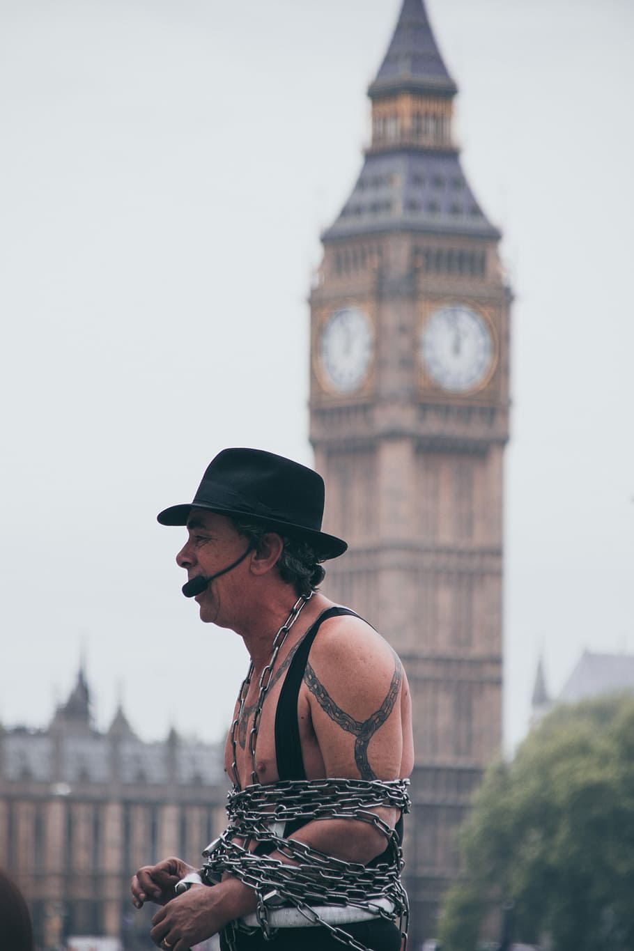 selective focus photo of man covered with chain with microphone with a view of big ben, man wearing hat standing outdoors HD wallpaper
