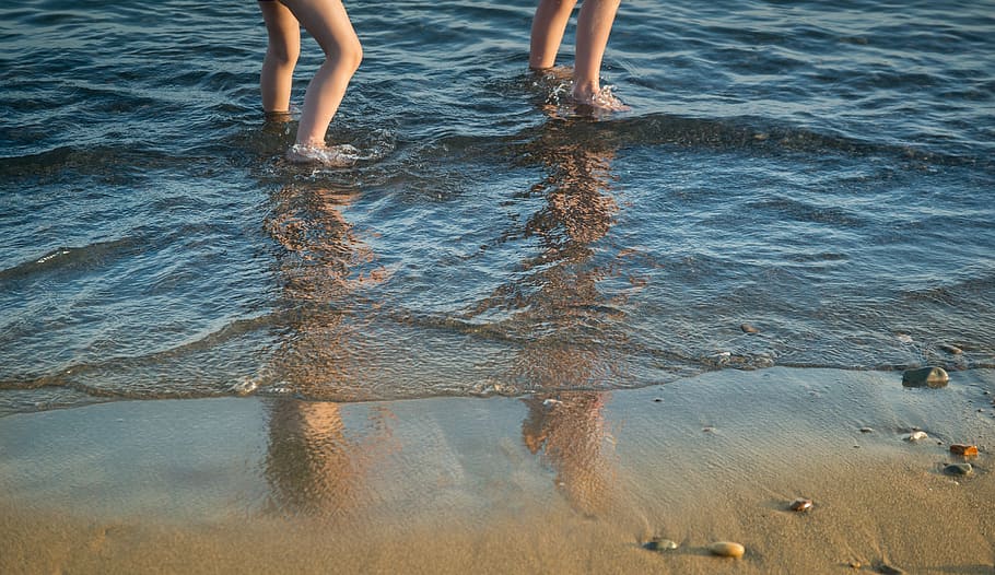 two people standing on body of water near brown sand, shoreline HD wallpaper
