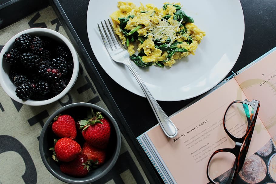 two bowls of blackberries and strawberries next to plate with dish and fork beside opened book with eyeglasses on top HD wallpaper