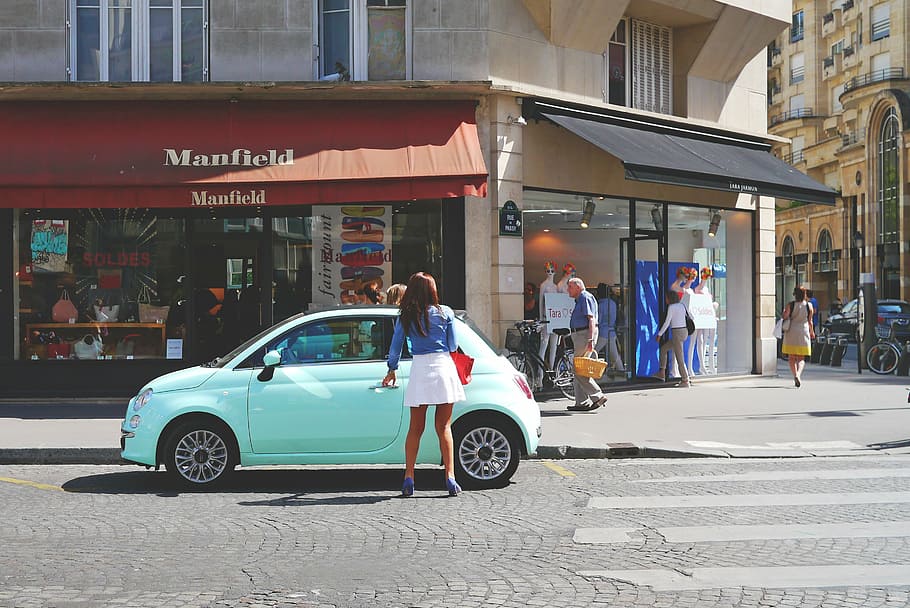 woman standing while holding blue FIAT 500 left door parking on street HD wallpaper