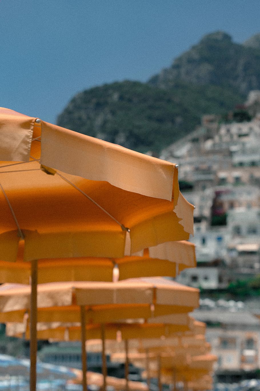 aligned orange patio umbrellas near mountain, shallow focus photography of yellow patio umbrellas