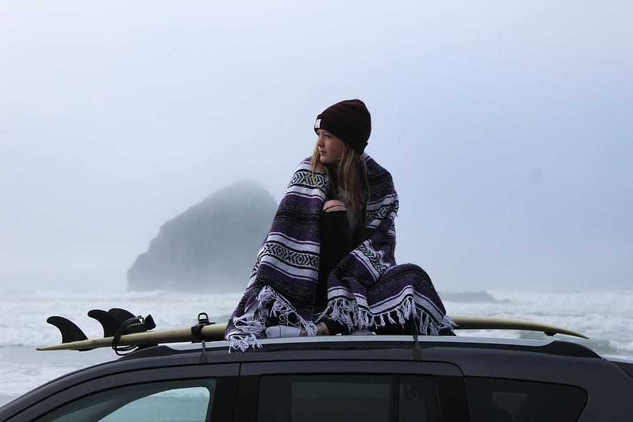 woman wearing beanie hat on vehicle roof, woman sitting on the top of a car with a surfboard, HD wallpaper