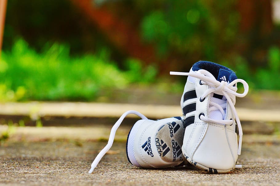 selective focus photography of pair of toddler's white-and-black adidas sneaker on ground