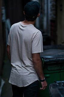 man wearing white shirt beside wheelie bin, man wearing white t-shirt, black pants and cap HD wallpaper