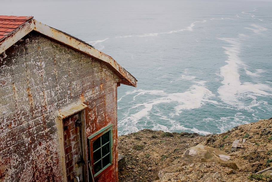 gray and red concrete house near the body of water, brown cabin on cliff HD wallpaper