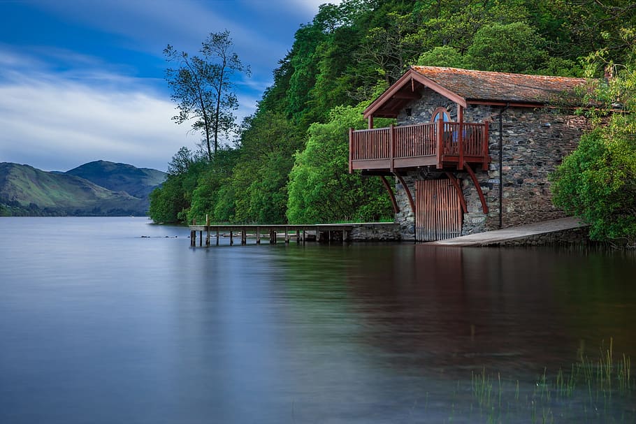 brown wooden house near body of water during daytime, boat house