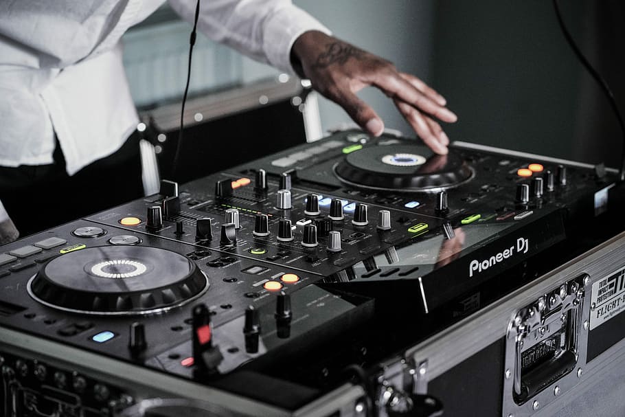person touching black terminal mixer, man using Pioneer DJ controller