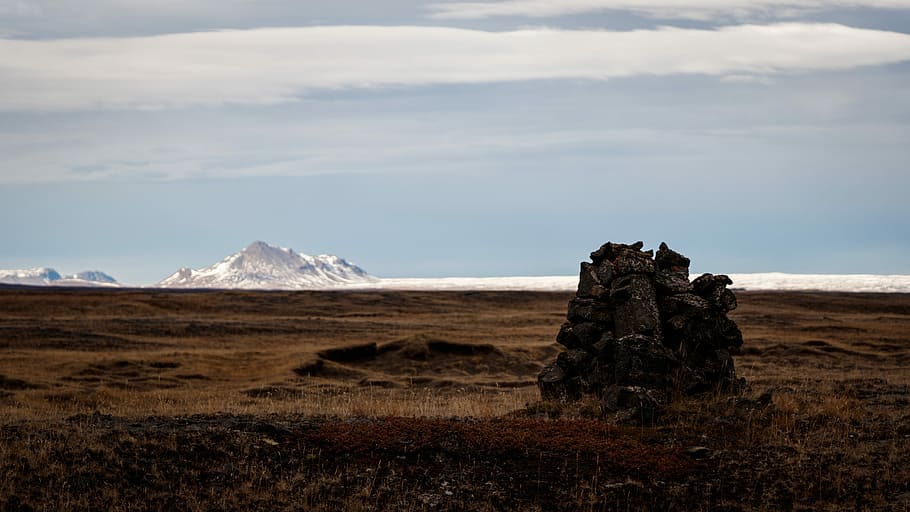 pile of rocks on plain under blue sky at daytime, mountain covered by snow HD wallpaper