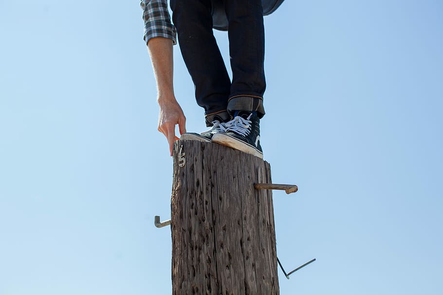 person on black pants standing in brown wooden log, outdoors