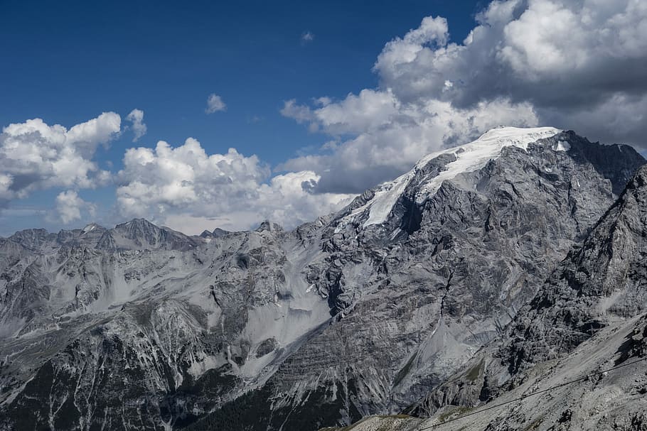 aerial photography of gray mountain range under clear blue sky during daytime, snow capped mountain under cloudy sky HD wallpaper