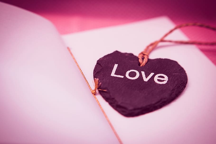 selective focus photography of black stone Love printed pendant on white paper sheet HD wallpaper