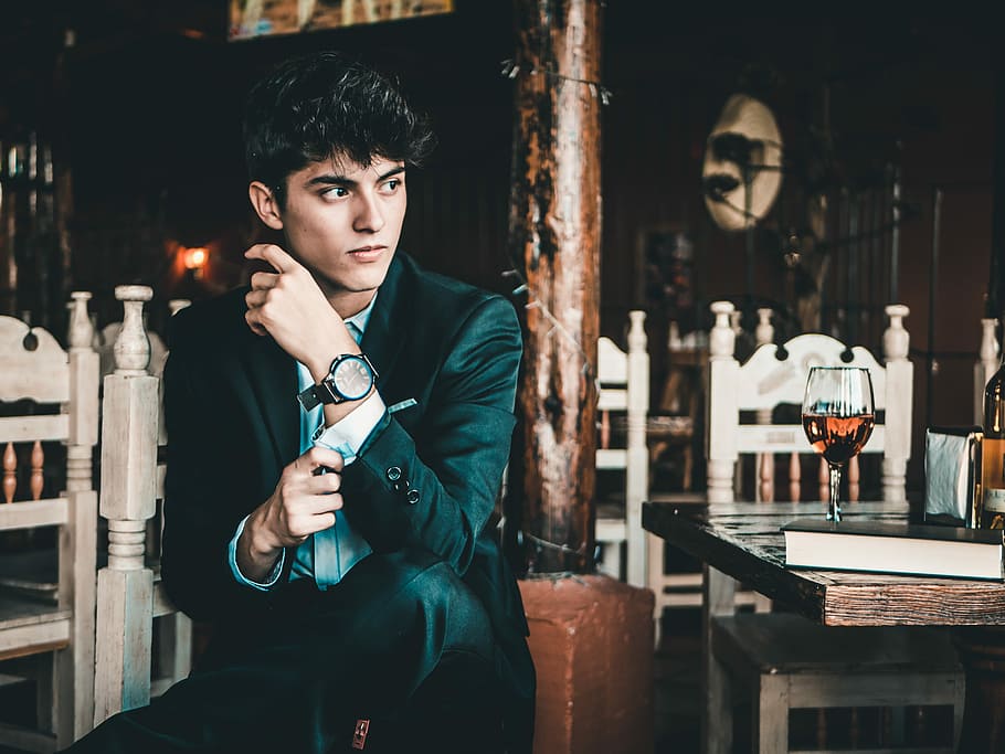 man sitting on chair near post and table, man touching his cufflink left suit jacket sleeve HD wallpaper