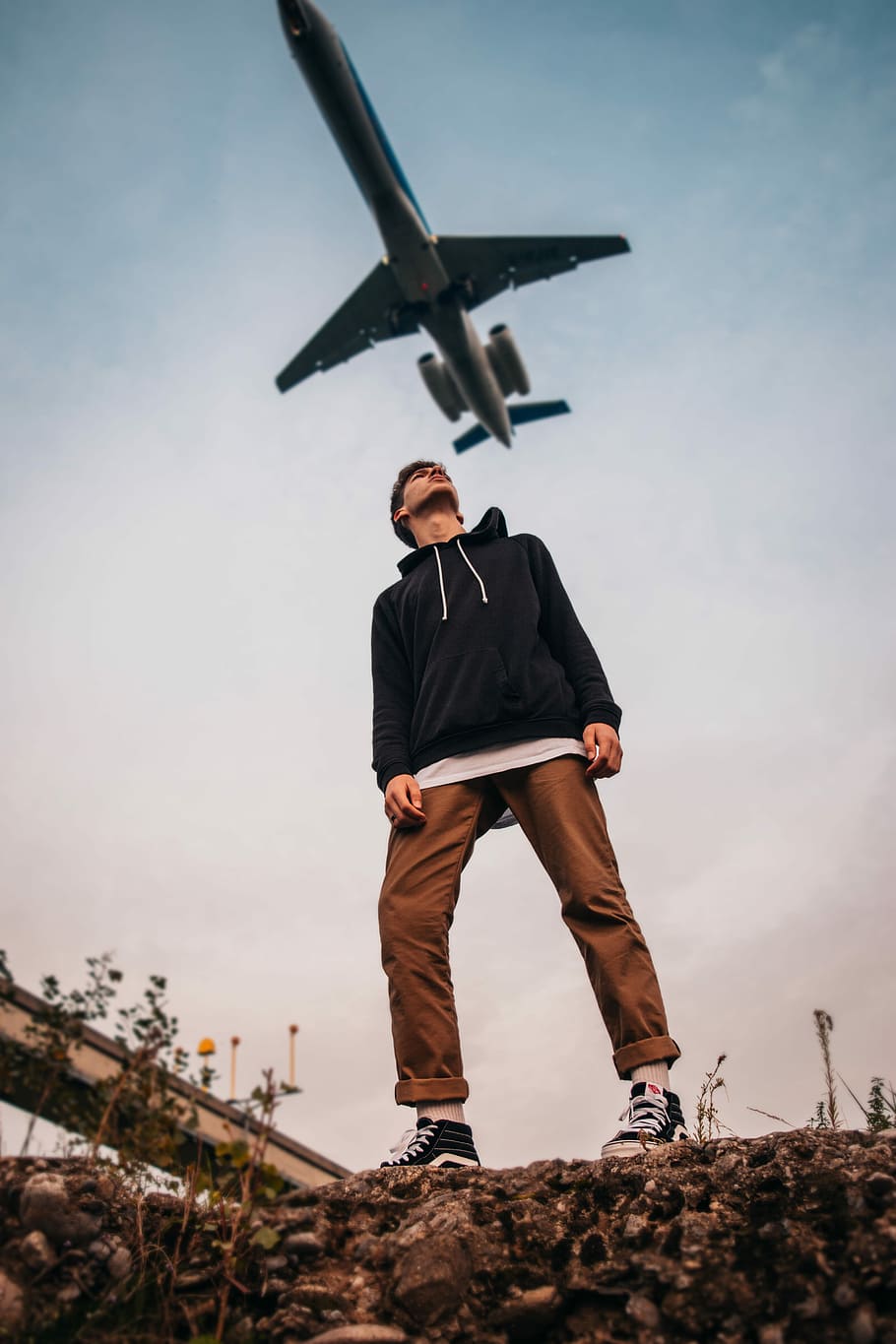 man looking up at flying airplane during daytime, low angle photography of man standing under flying airline, HD wallpaper