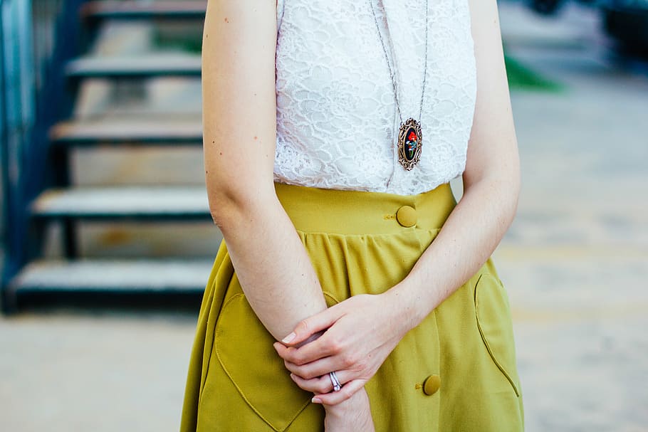 person wearing white lace top standing beside staircase, photo