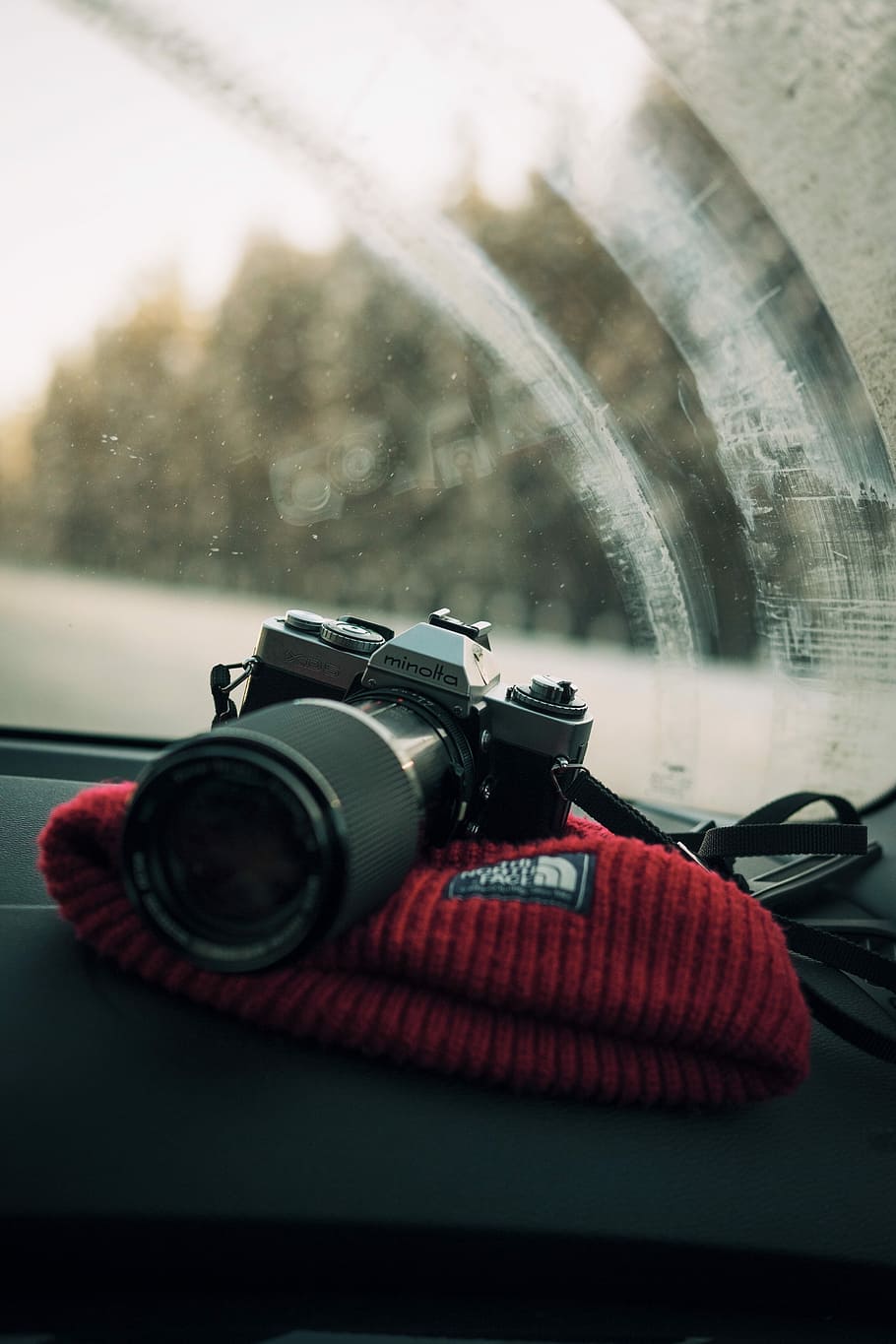 photo of gray Minolta DSLR camera on glove compartment, minolta DSLR camera on The North Face beanie cap inside vehicle during daytime HD wallpaper