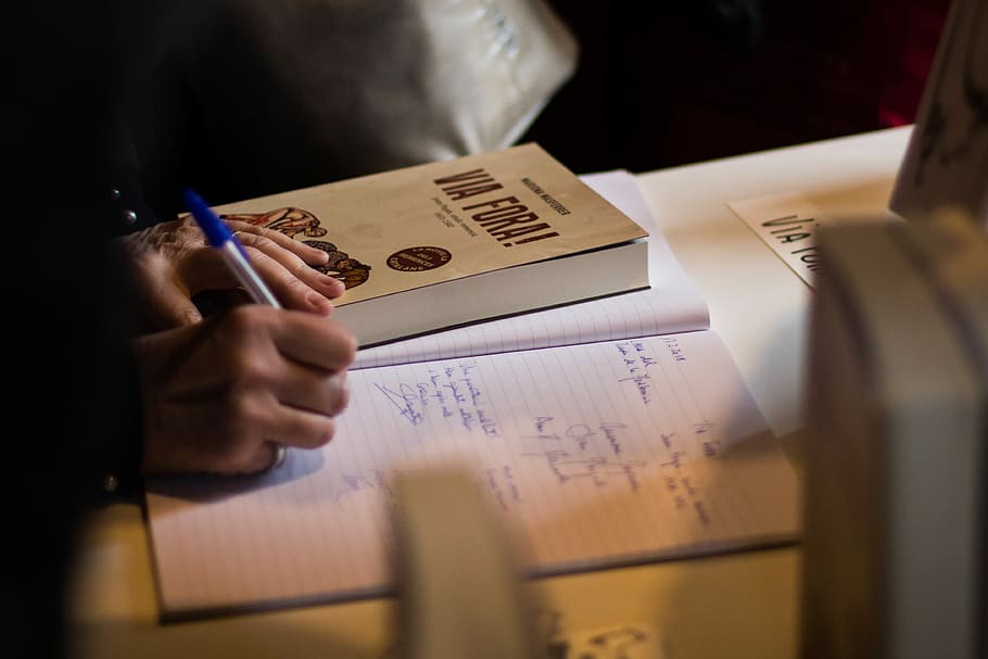 person writing on notebook near book, person writing on white lined paper HD wallpaper