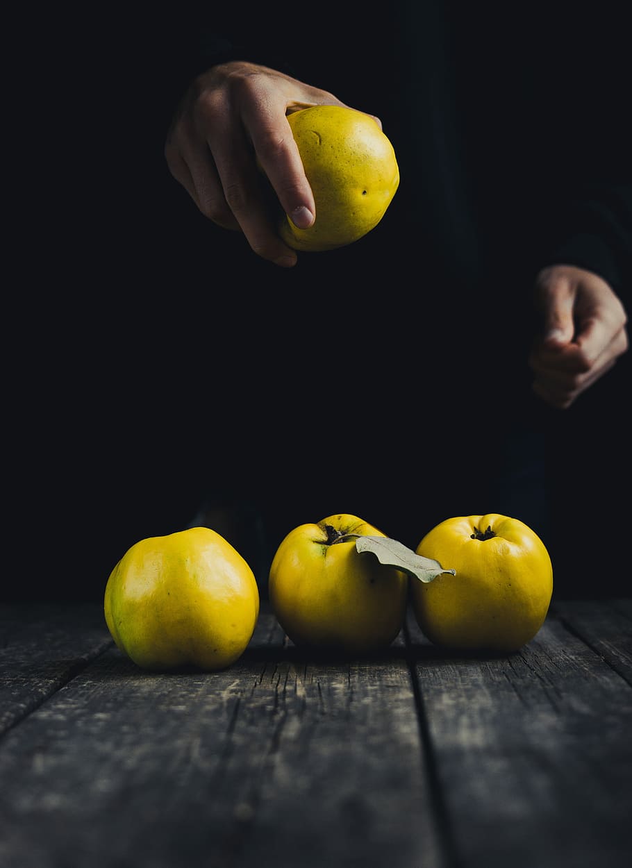 Quince in hand and on dark wooden background, person holding yellow fruit HD wallpaper