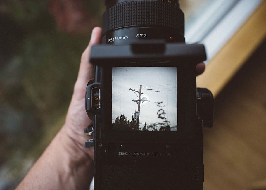 person holding black DSLR camera, black camera at photo of electric post HD wallpaper