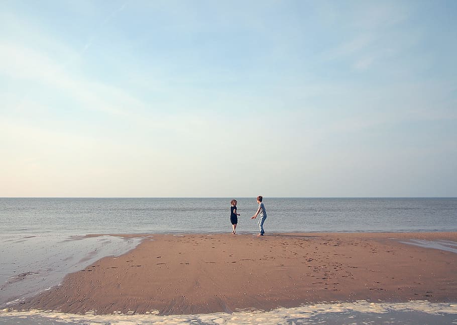 two woman playing in shoreline, two person standing on front of ocean HD wallpaper