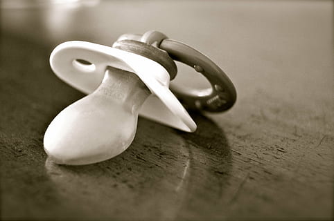 closeup photo of greyscale pacifier on brown wooden table, dummy HD wallpaper