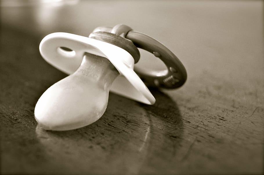 closeup photo of greyscale pacifier on brown wooden table, dummy HD wallpaper