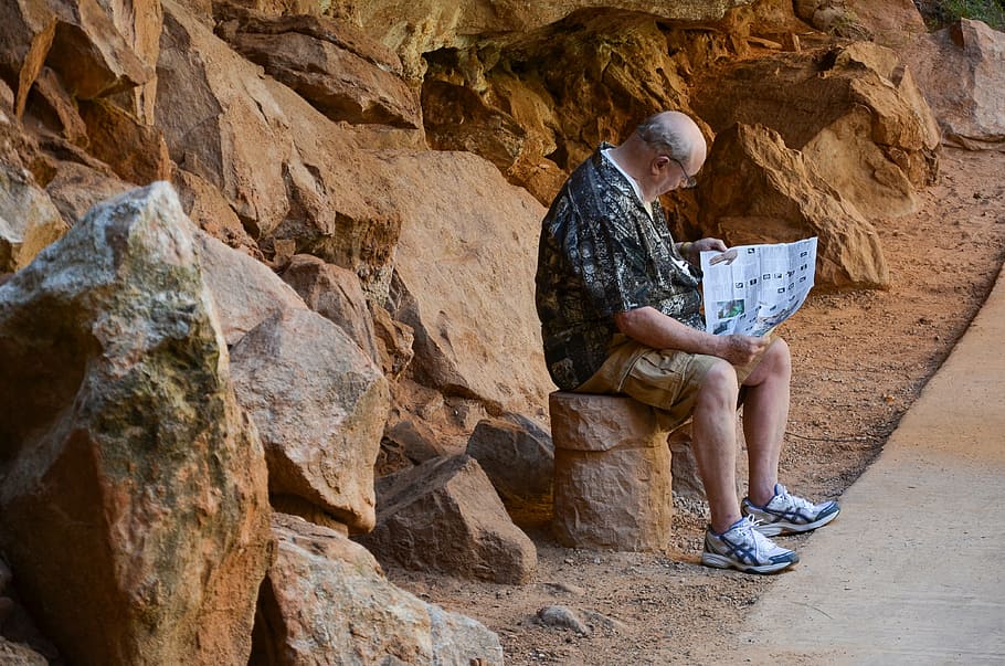 man sitting on rock reading newspaper, usa, america, trail, zion national park