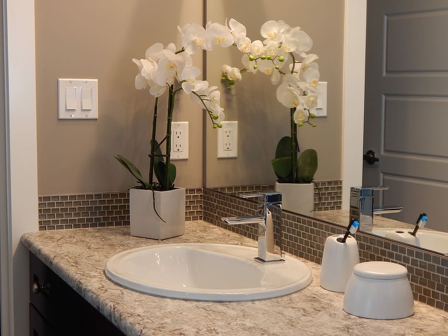 white ceramic sink with stainless steel faucet near white orchids