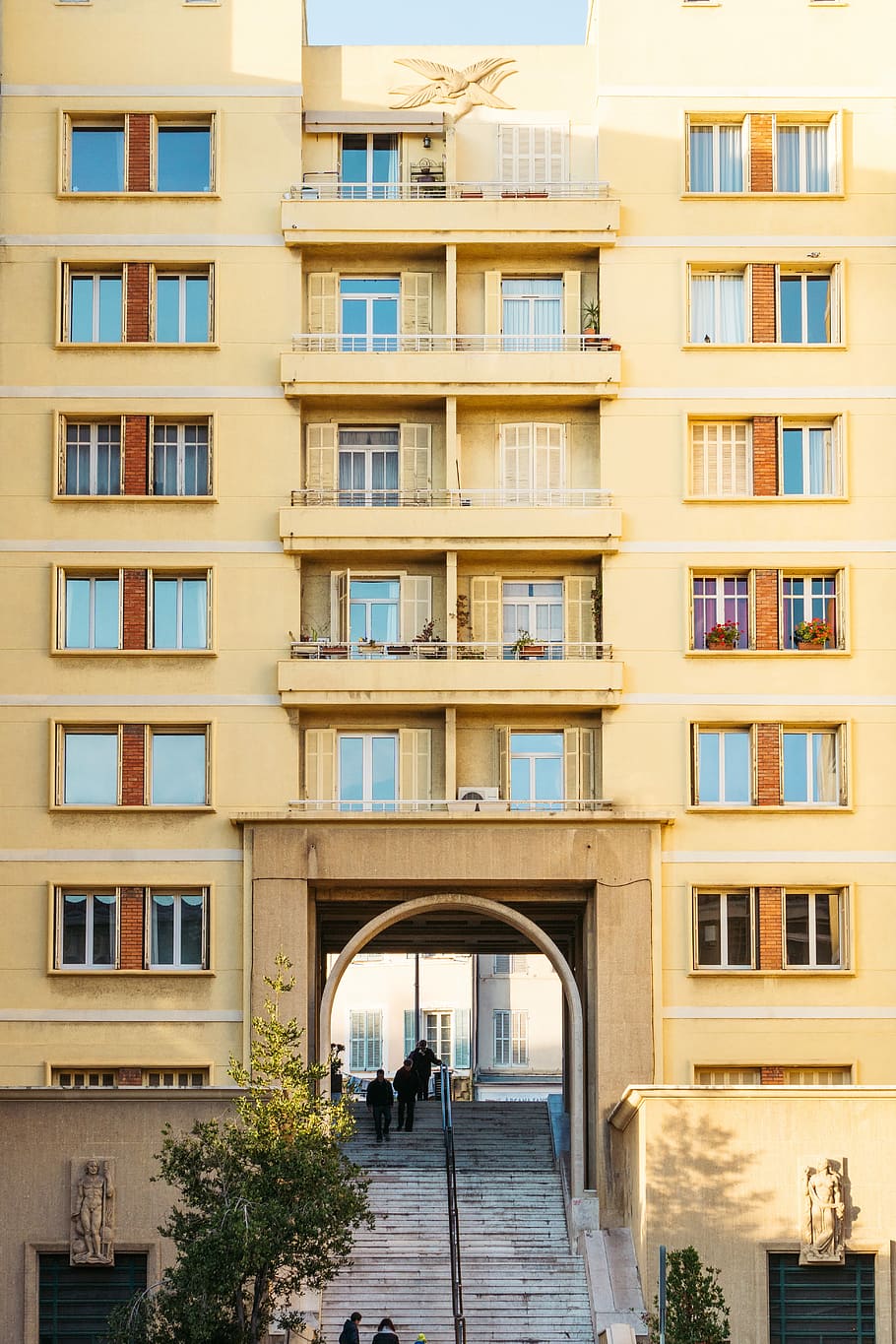 people on stairs under beige concrete building, brown painted building during daytime HD wallpaper