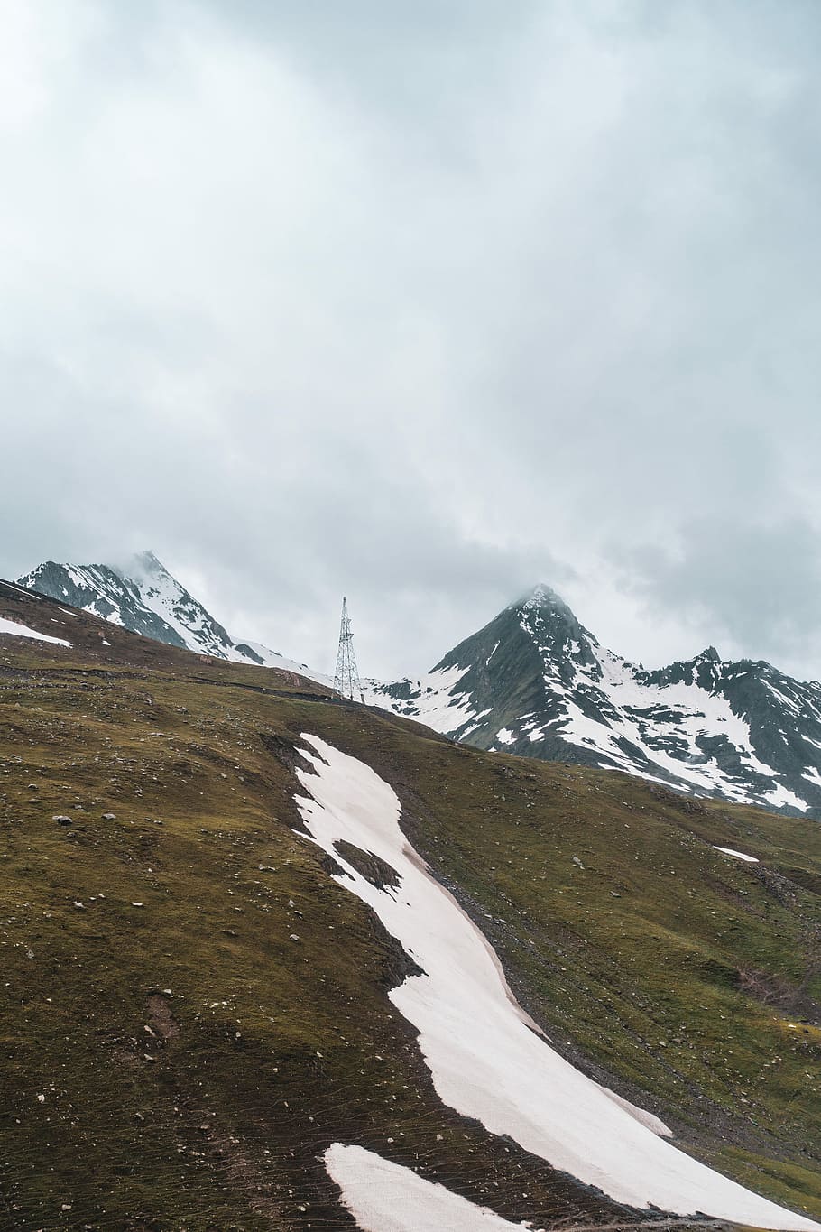 gray concrete tower on brown mountain under cloudy sky, landscape photography of snowy mountain