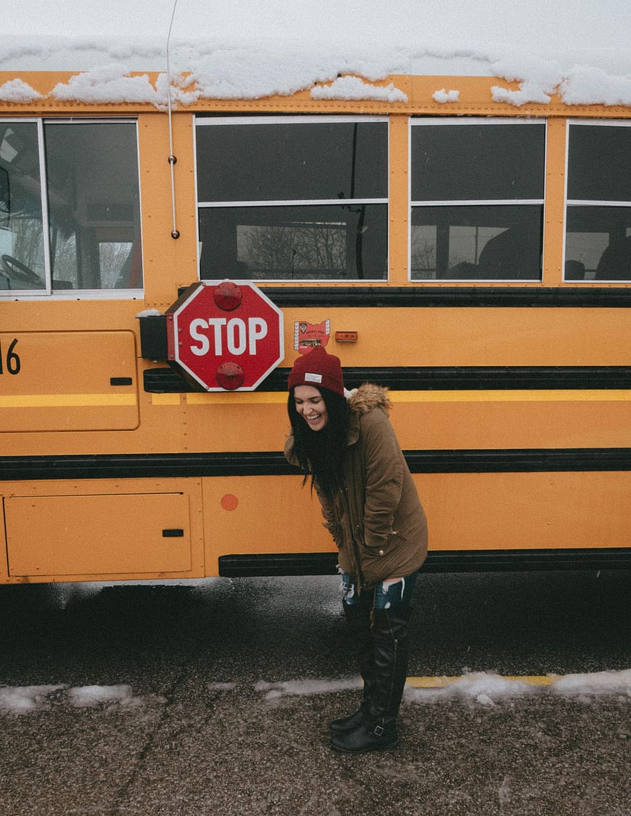 woman in brown parka coat standing in front of yellow bus, woman standing in front of school bus, HD wallpaper