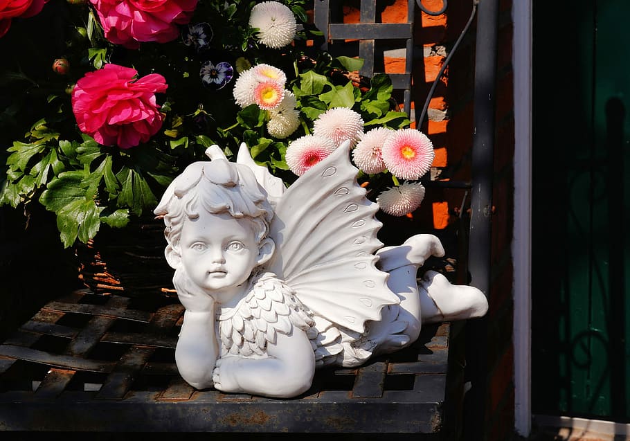 cherub ceramic figurine near white petaled flowers, stone statue