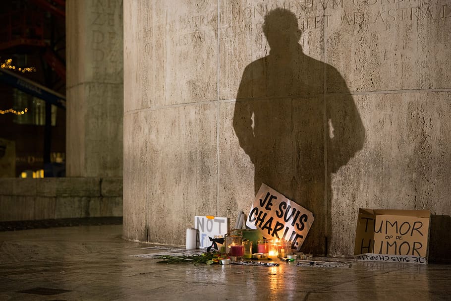 shadow of man standing in front of lighted candles with signage HD wallpaper