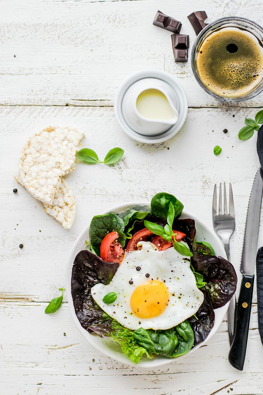 flat-lay photography of lettuce with fried egg and flatbread, vegetable salad dish with sunny side up egg in flat lay photography