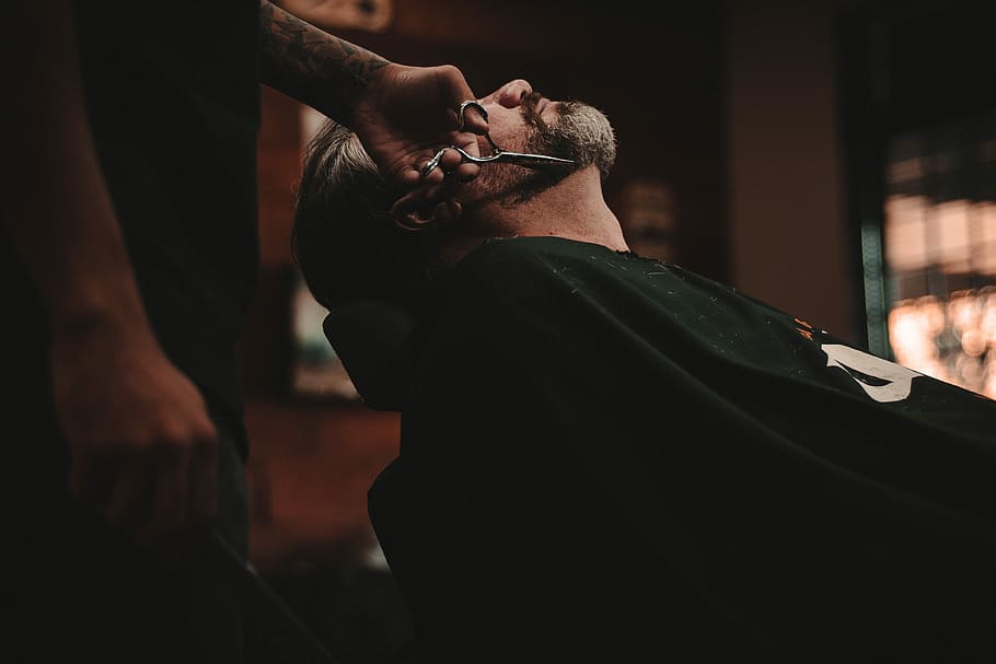 man sitting on barber's chair, man cutting another man's beard HD wallpaper