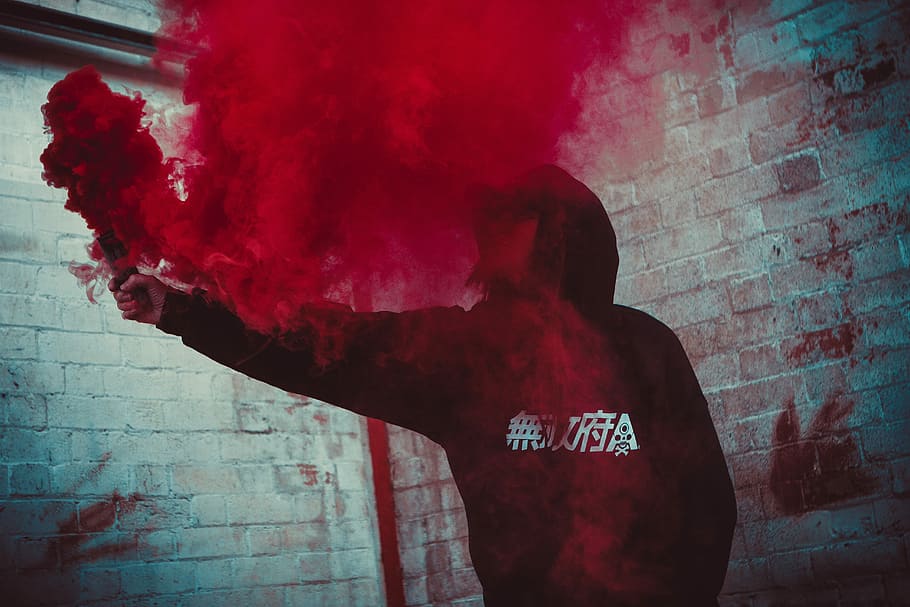 person holding red smoke bonb, man holding red flare smoke, paint