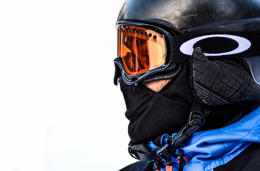 person wearing orange Oakley snow goggles with black frame, snowboard