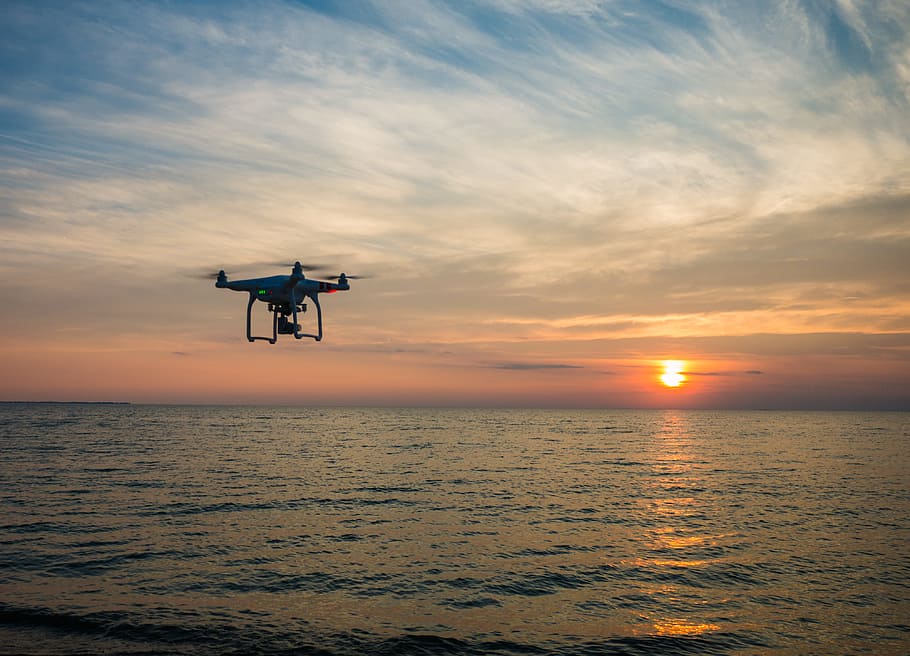 quadcopter flying over body of water, drone flying above body of water under white skies at golden hour HD wallpaper